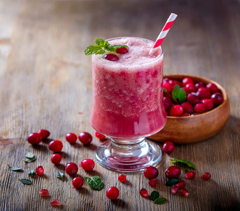 apple and cranberry smoothie in a glass surrounded by fresh cranberries