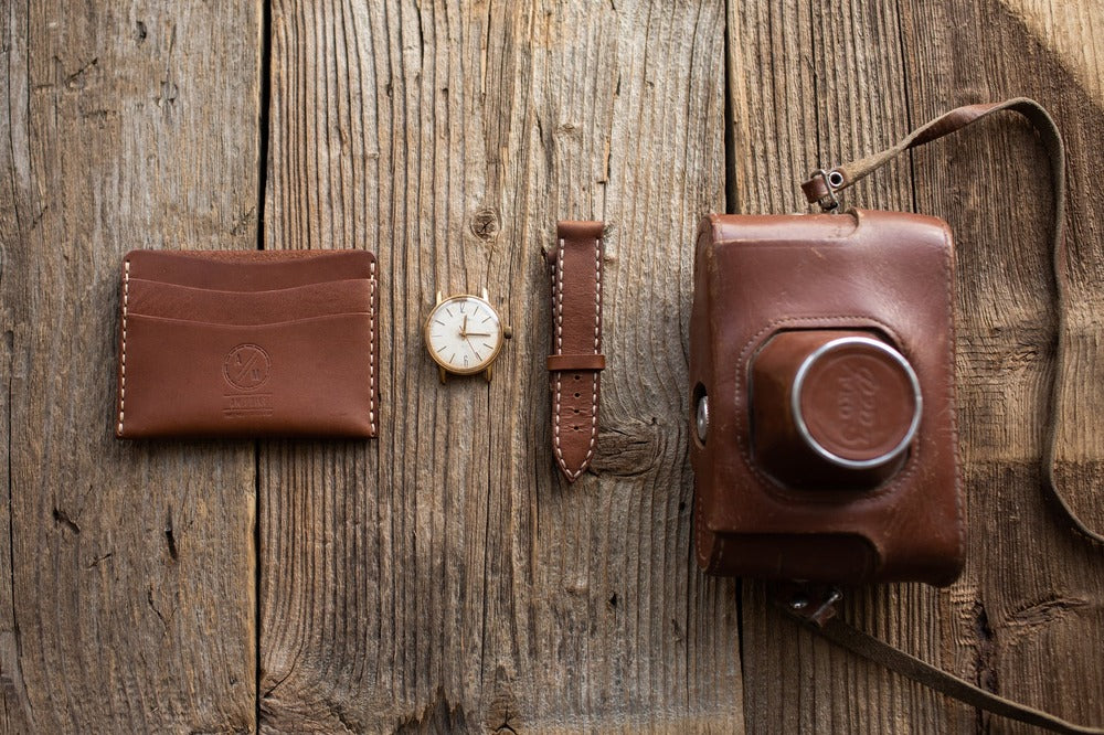 きれいに手入れされた革財布と革ベルト、革のカメラケースの写真
