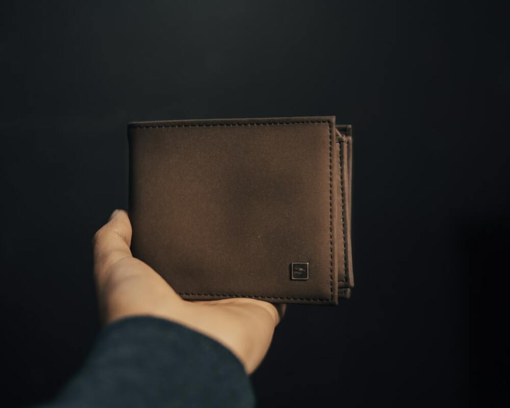 ブラウンの革財布を手に持つ画像