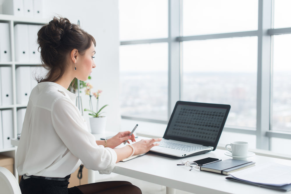 オフィスで女性がパソコンに向かい仕事をしている
