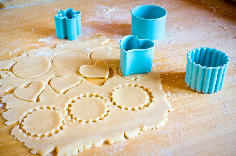 Photo of cookie dough being cutout using shape cookie cutters