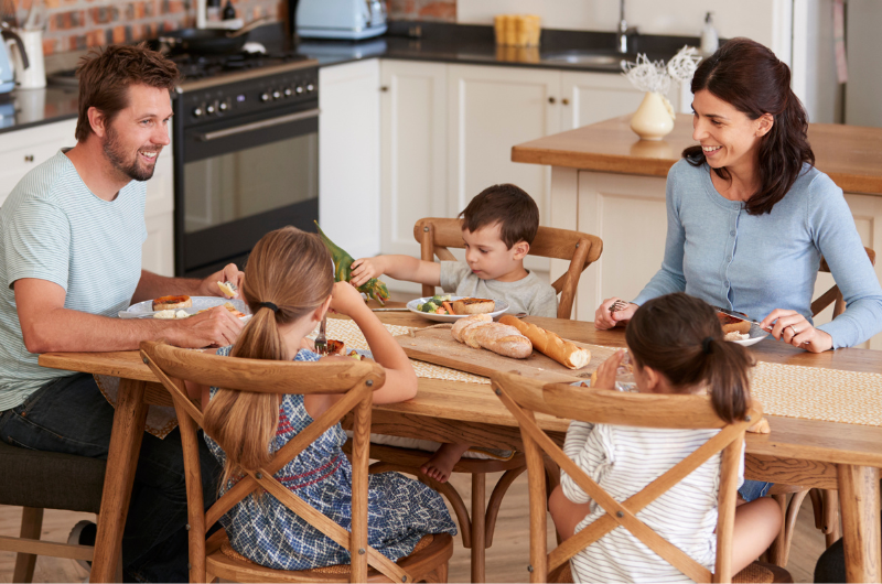 Family eating dinner together at the dinning table, mom, dad and three young kids