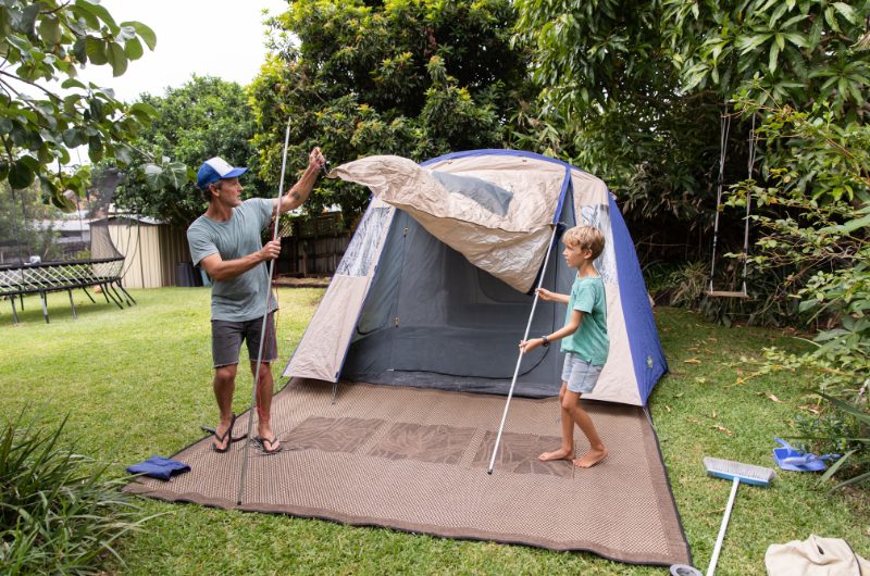 father and son setting up a tent in the backyard