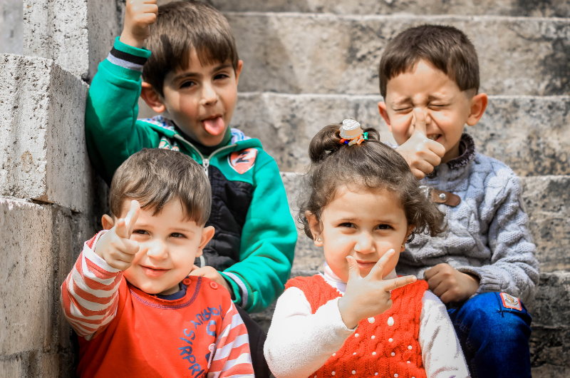 photo of four kids sitting on steps outside making funny faces