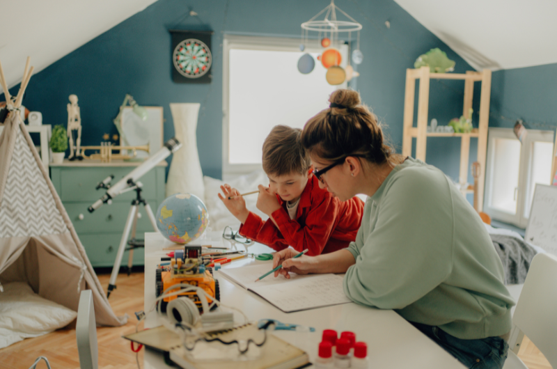 homeschool mom working with son at desk