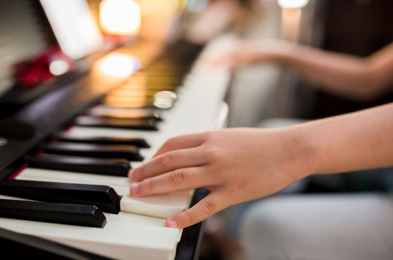 close-up photo of a childs hands playing the piano