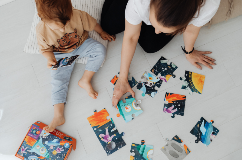 mother and young child on the floor working on a jig-saw puzzle 