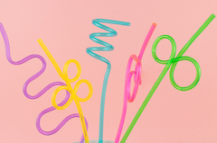 five fun, bright colored, twisty straws against a pink background