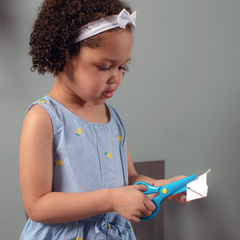 young girl cutting paper with kids safety scissors