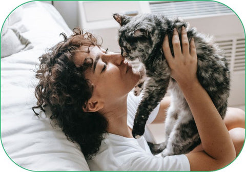A woman holds up her healthy cat and gives it a gentle kiss