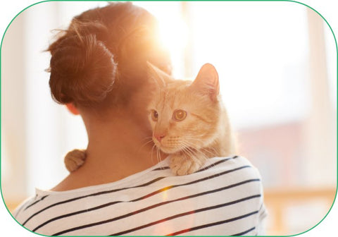 A woman tenderly holds a cat.