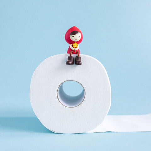 red girl miniature toy sitting on a roll of toilet paper