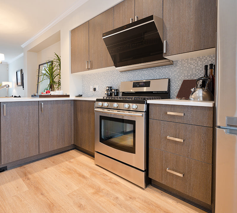 JQG01 range hood installed above a stainless steel stove in a wood kitchen.