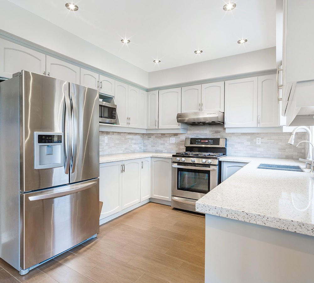 Modern white kitchen with stainless steel appliances, including a UQS3001 Under-Cabinet Range Hood.