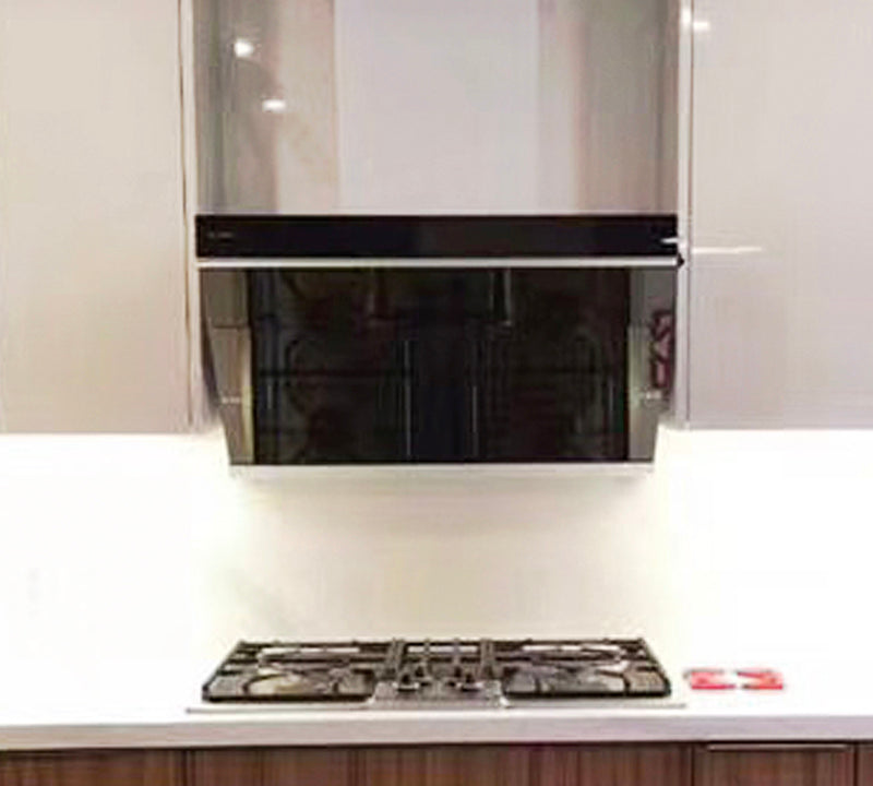 Onyx Black Tempered Glass JQG05 Series under cabinet range hood above a black stove top in a gray kitchen.