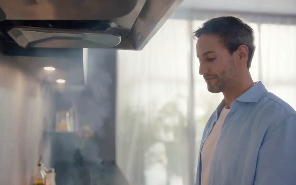 Hombre cocinando debajo de una campana extractora FOTILE