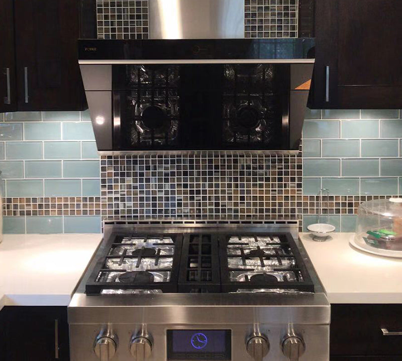 Onyx Black Tempered Glass JQG05 Series under cabinet range hood above a stainless steel stove in a blue kitchen.