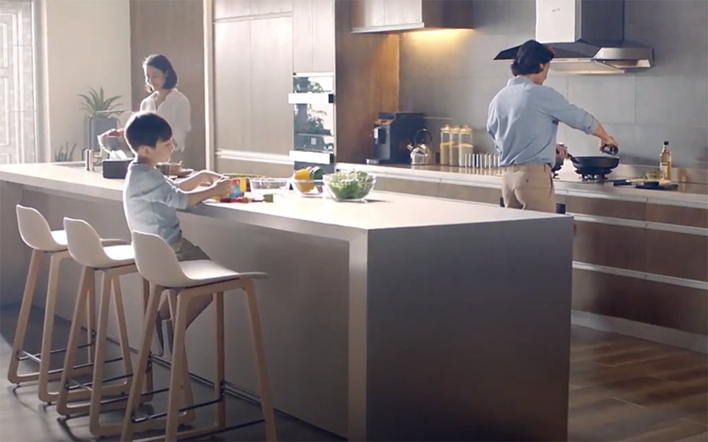 Family cooking dinner in a modern kitchen with a EMG9030 Range Hood.