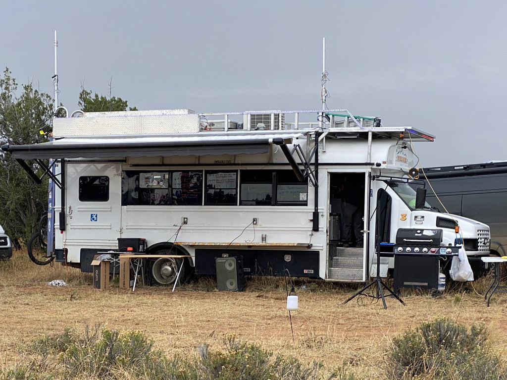 White school bus converted for dwelling at a high desert event.