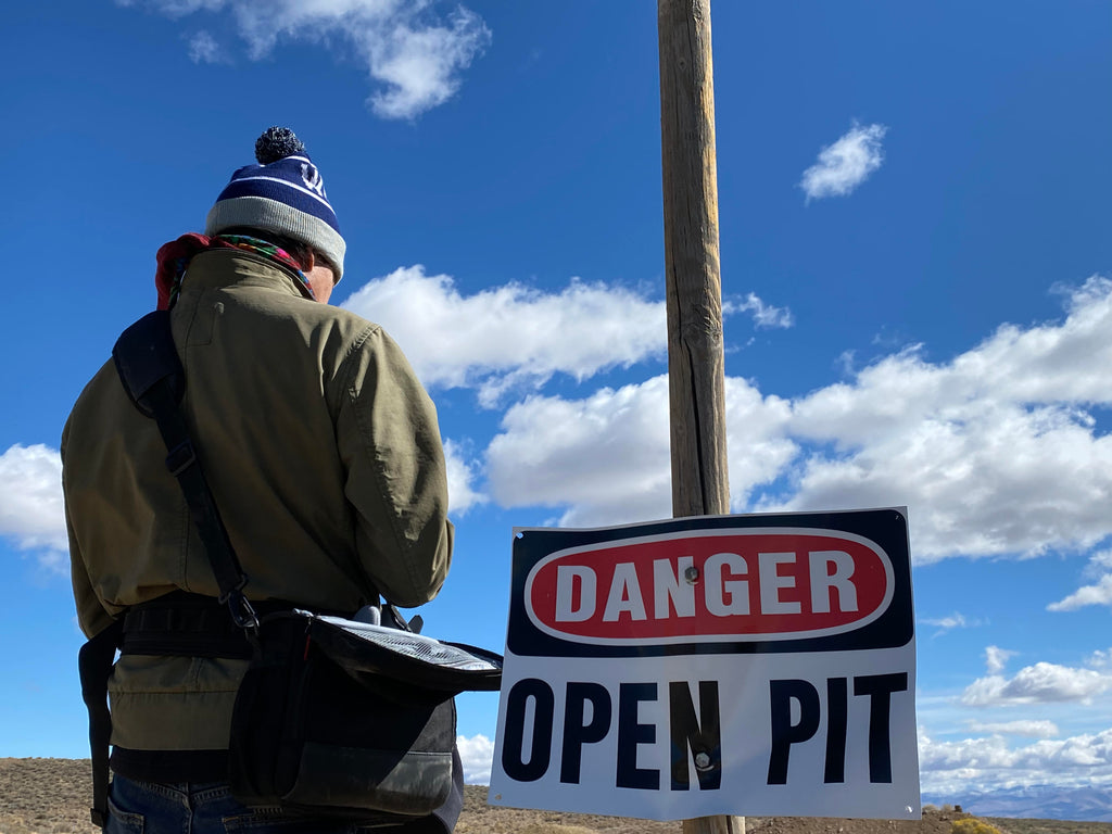 James Foguth standing by a sign that says DANGER: OPEN PIT