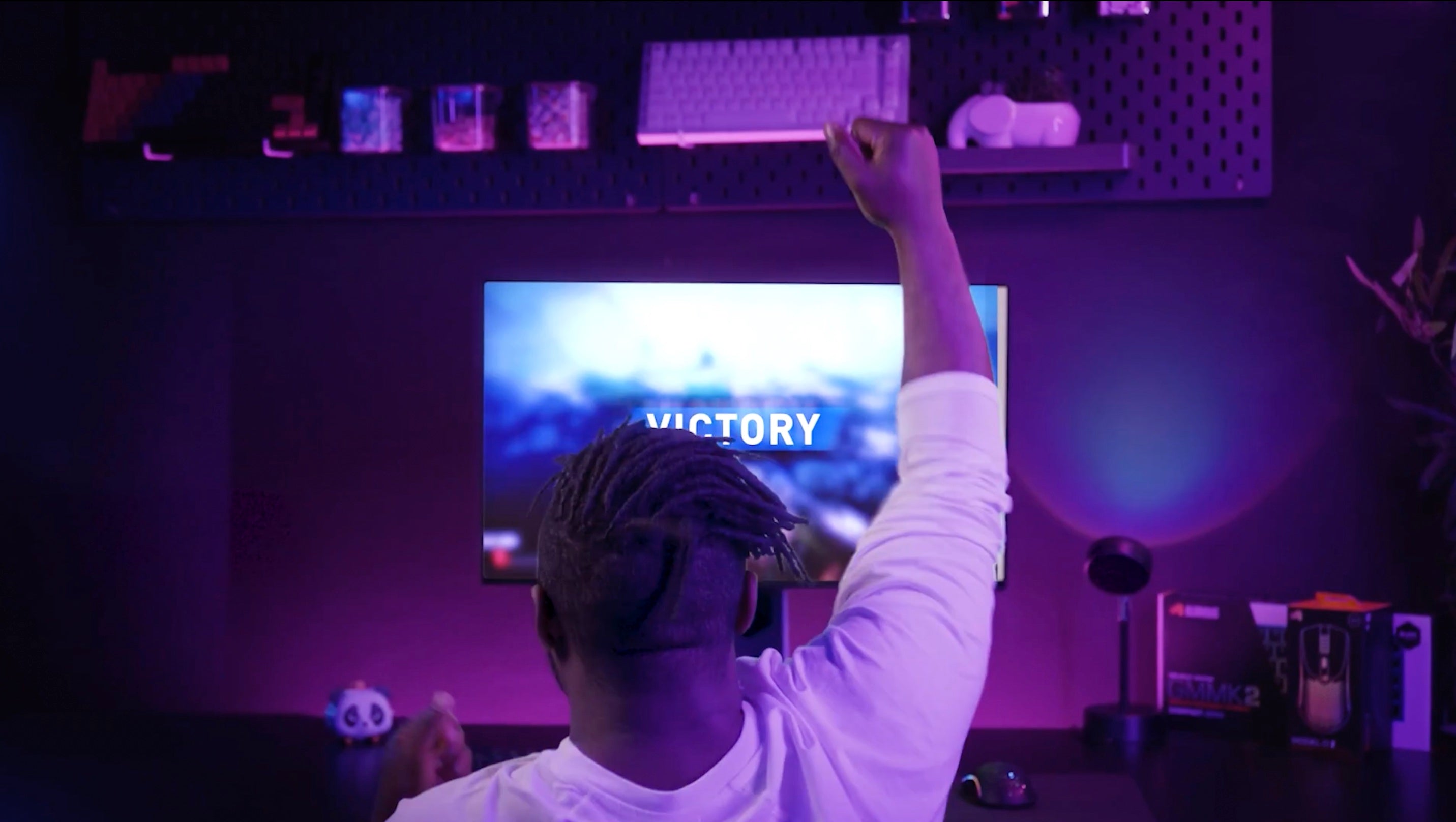 A gamer playing a video game on PC with his hands in the air because he won.