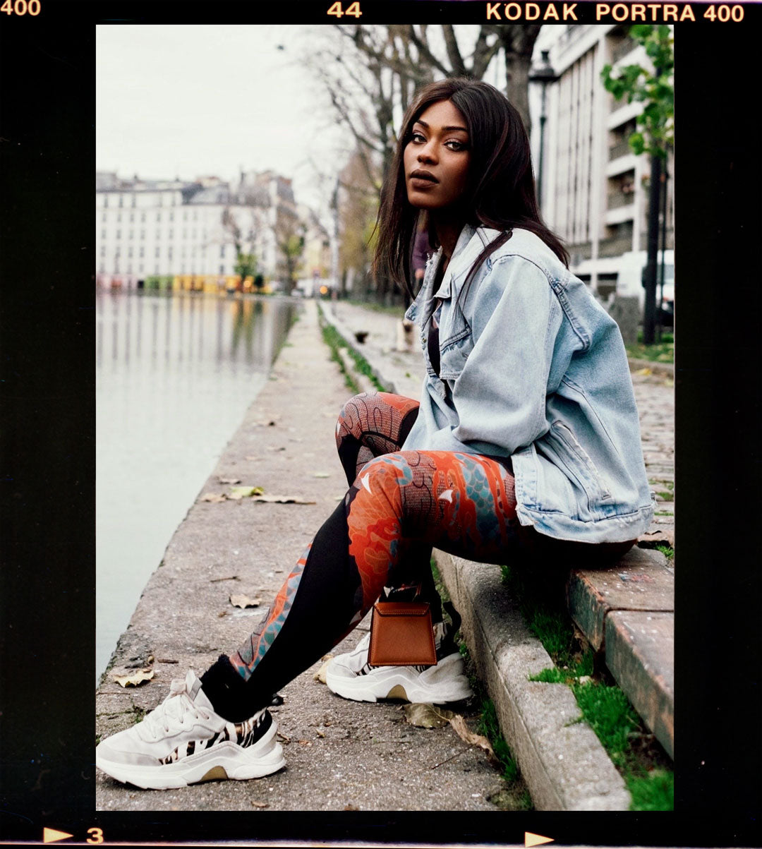 Black woman wearing Zoelle Bybs Xculpt dragon scarlet leggings on the banks of a river in Paris