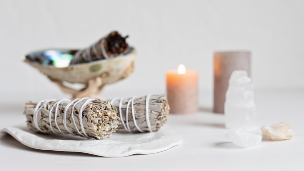 Mugwort smudge sticks rest on a table with assorted crystals and candles