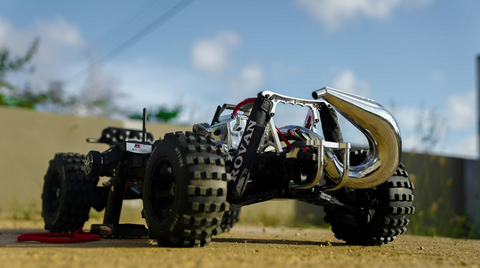 A close-up of a bare RC car with gripped racing wheels