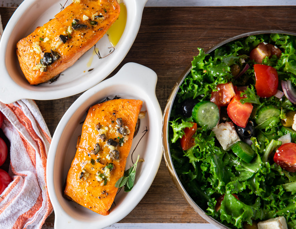 Two baked salmon fillets and a bowl of garden salad.
