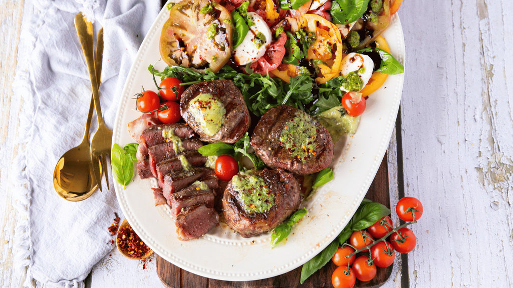 Grilled Bacon Wrapped Tenderloin Steak on a plate with a side of Caprese Salad