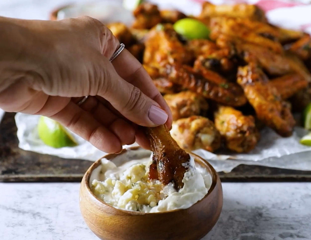 Hand dipping Sealand air fryer chicken wings into blue cheese sauce