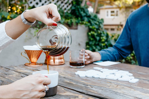 People sitting at wooden table sharing brewed coffee