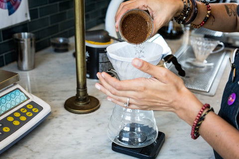 pouring fresh coffee grounds into a hario v60