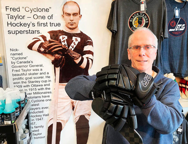 Mark Taylor posing in front of a picture of his famous grandfather, hockey legend Fred "Cyclone" Taylor
