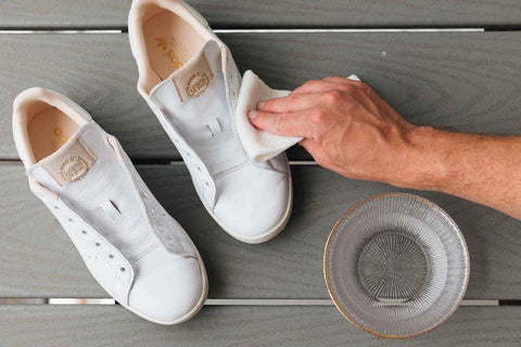 Cleaning sneakers with acetone. On the picture you can see a hand cleaning white suede sneakers with a white cloth