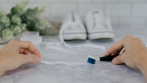 how to get paint or dirt of shoelaces. Piture is off a hand cleaning white shoelaces with a toothbrush 