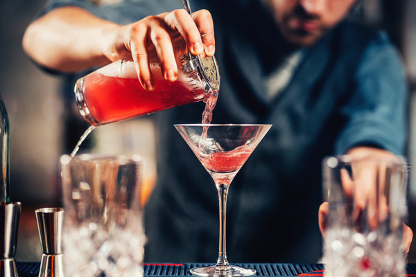 a bartender pouring vodka cosmopolitan cocktail