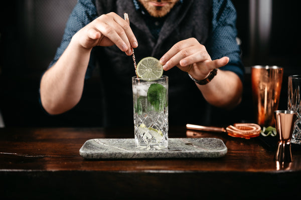 bartender adding lime to gin and tonic in bar
