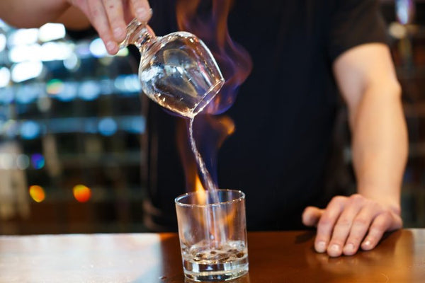 bartender holding glass over burning Sambuca
