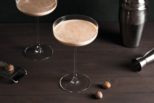 brandy alexander in two cocktail glasses with nutmeg grater and bar tools