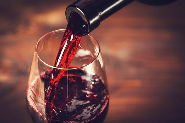 close up of red wine being poured into glass