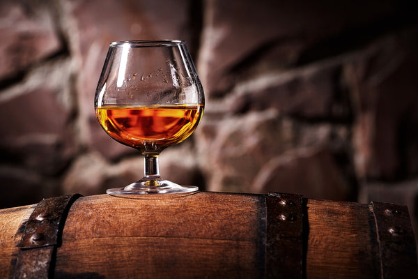 glass of cognac on wooden barrel