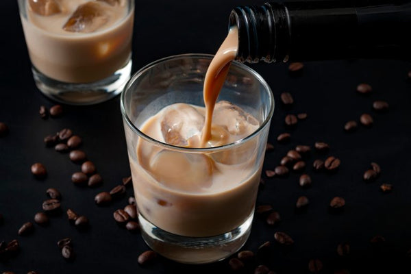 irish cream poured into two glasses on black table