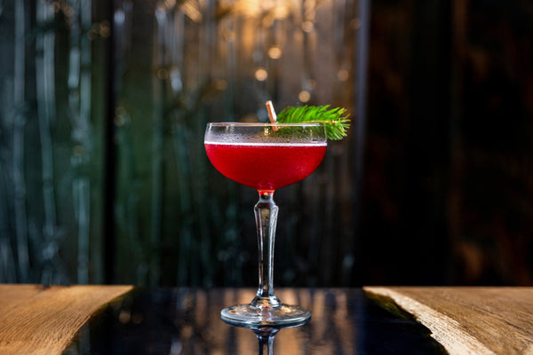 red cocktail with garnish on bar table