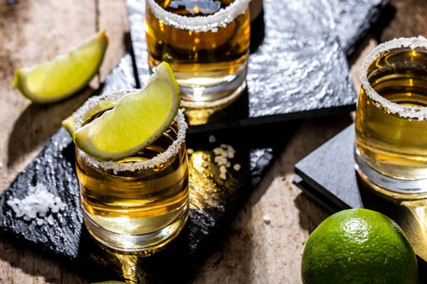 shots of tequila with lime in salt rimmed shot glasses