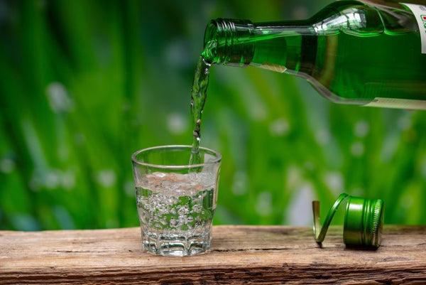 soju being poured in shot glass with plant background