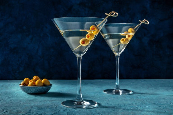 two dirty martinis with olives and bowl of olives