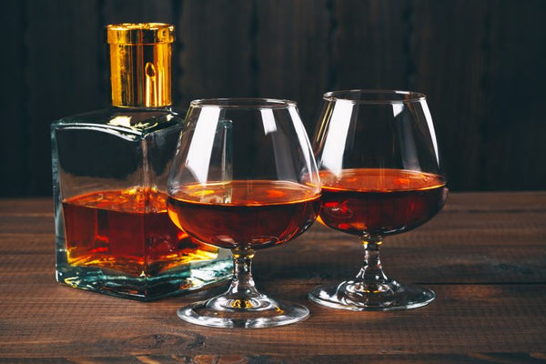 two glasses of brandy with brandy in glass liquor bottle