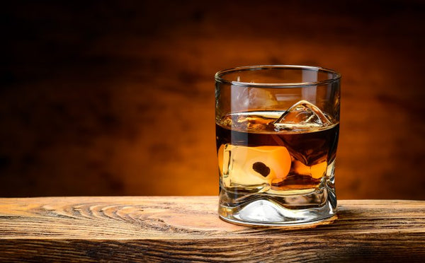 whiskey in glass with ice with brown background