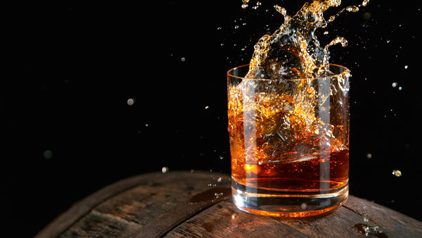 whiskey splashing out of cocktail glass with black background